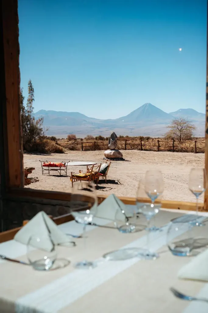 Mesa montada con copas y vajilla frente a paisaje desértico con volcán en San Pedro de Atacama